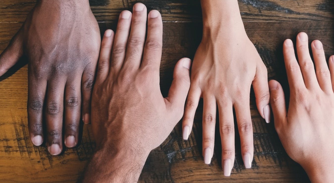 Hands on a table from different races and ethnicities