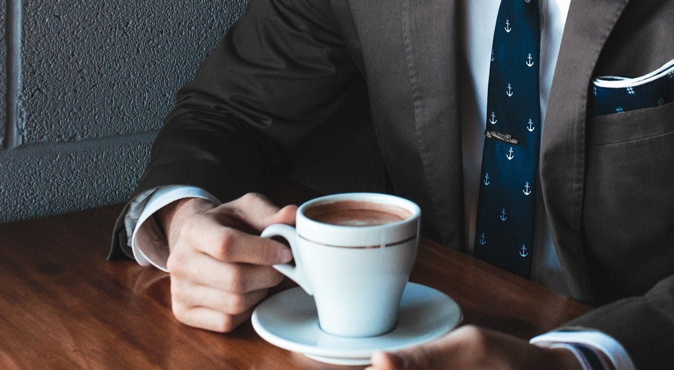 Man in suit at table with coffee