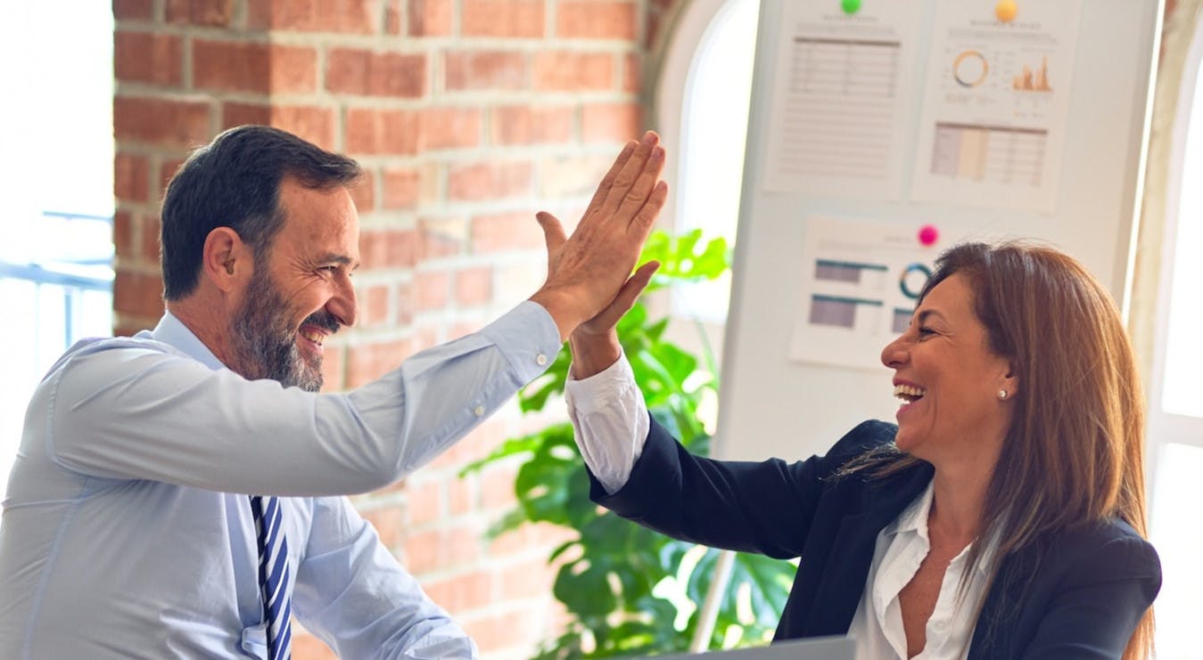 Business man and woman give high five while smiling